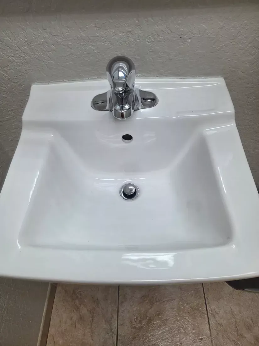 Wall-mounted restroom sink and chrome faucet polished clean
