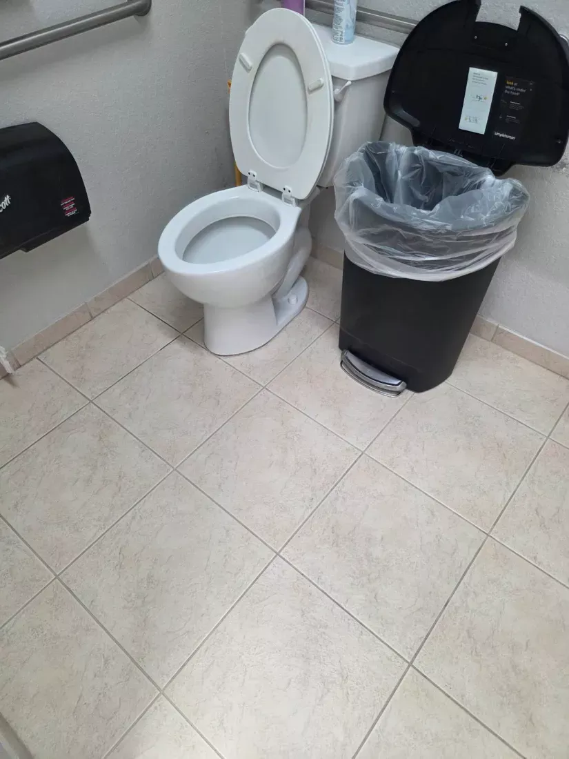 Commercial restroom with the toilet sanitised and the tile floor mopped
