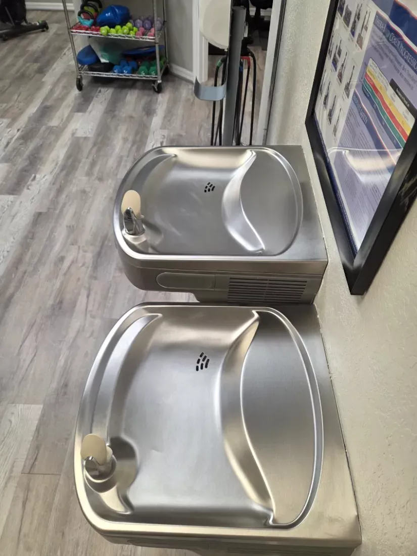 Stainless drinking fountains wiped down and polished in a clinic hallway
